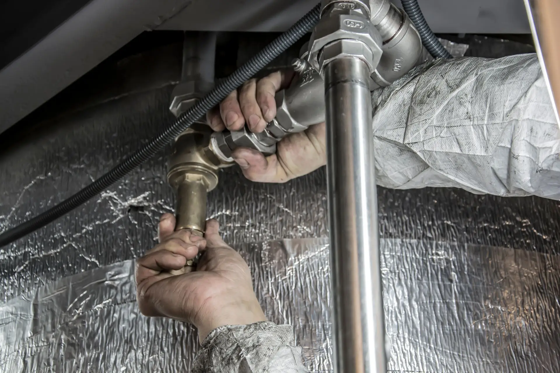 Plumber tightening fittings on a water line during a water heater installation